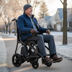 Man in a wheelchair on a sidewalk with a winter setting