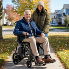 Man in a wheelchair being pushed by a woman on a sidewalk with autumn leaves and houses in the background.